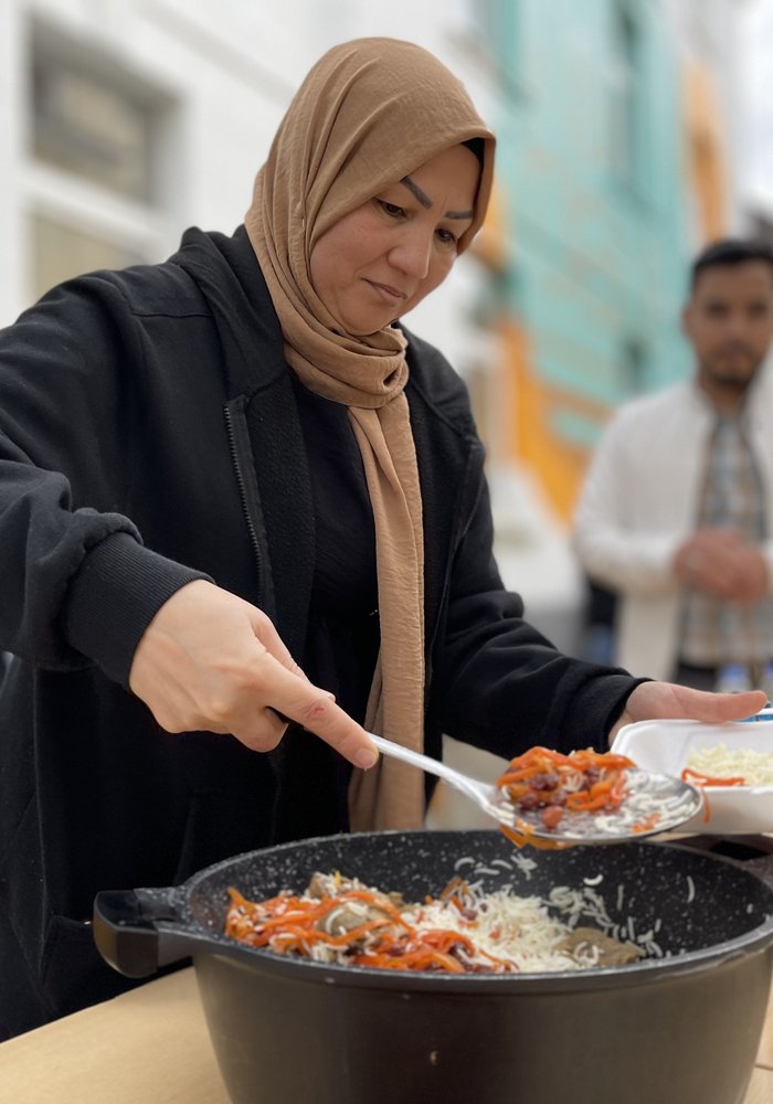 Eine Frau nimmt sich Essen aus einem Topf