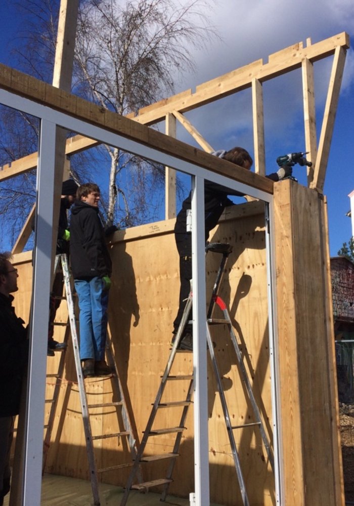 Vier Menschen, die ein Holzgerüst bauen.