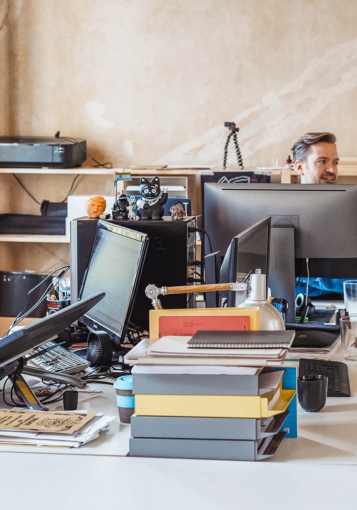 Ein Büro in dem drei Menschen an Computern sitzen und arbeiten.