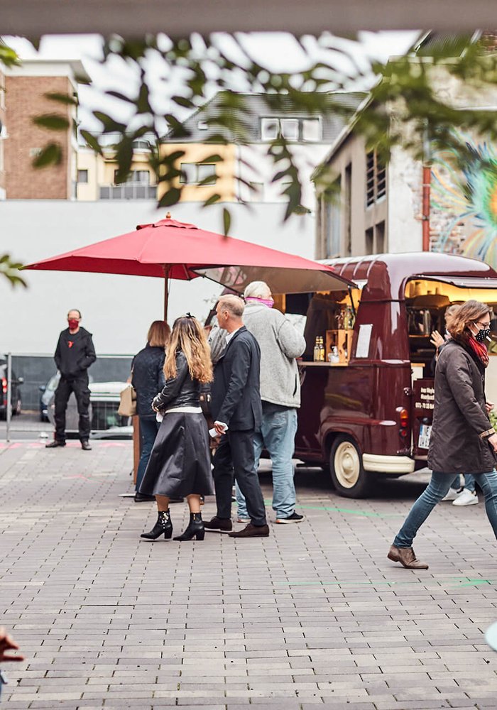 Ein Platz, auf dem ein mobiler Kaffeestand steht, drum herum sind Menschen.