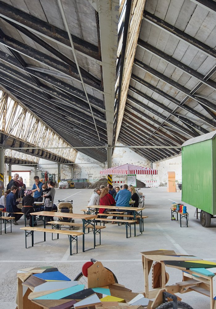 Die Shedhalle mit Sitzbänken und einem grünen Bauwagen.