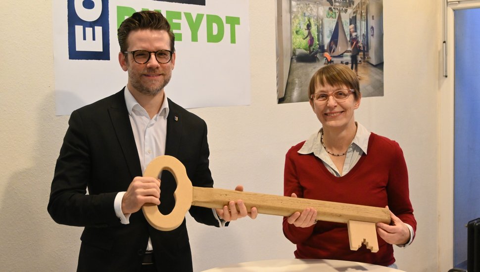 Viktoria Hoehl und OB Felix Heinrichs halten gemeinsam einen großen Holzschlüssel.