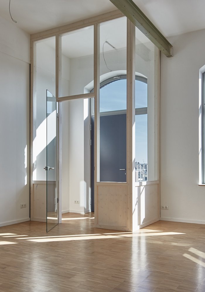 Ein heller leerer Raum mit hohen Decken und großen Fenstern.