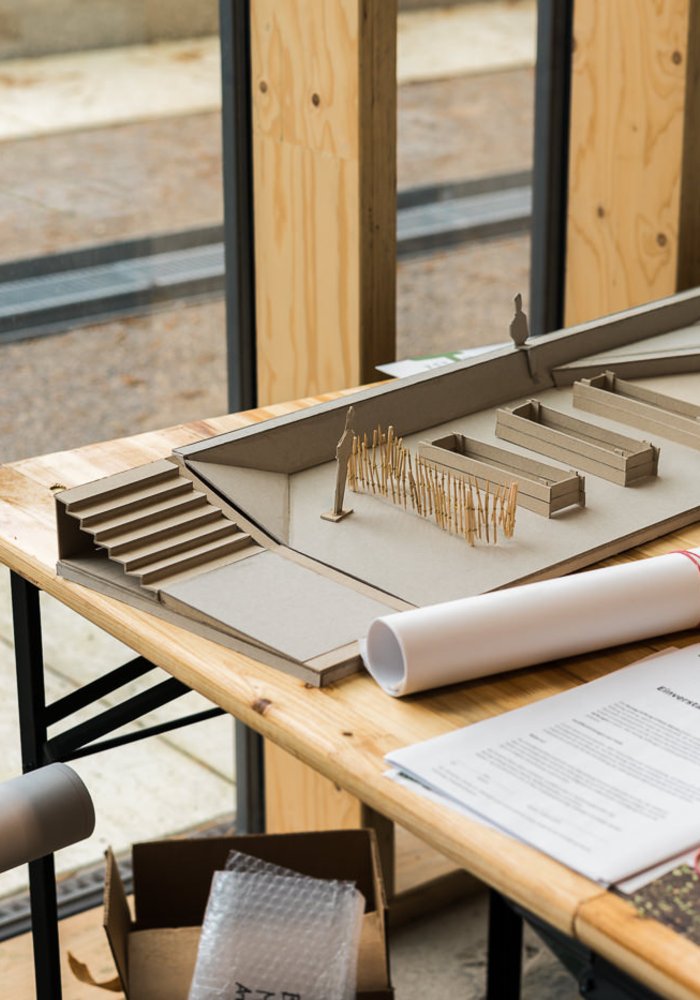 Der Anfang eines Architektur-Modells, welches auf einem Tisch liegt zusammen mit weiterem Material.