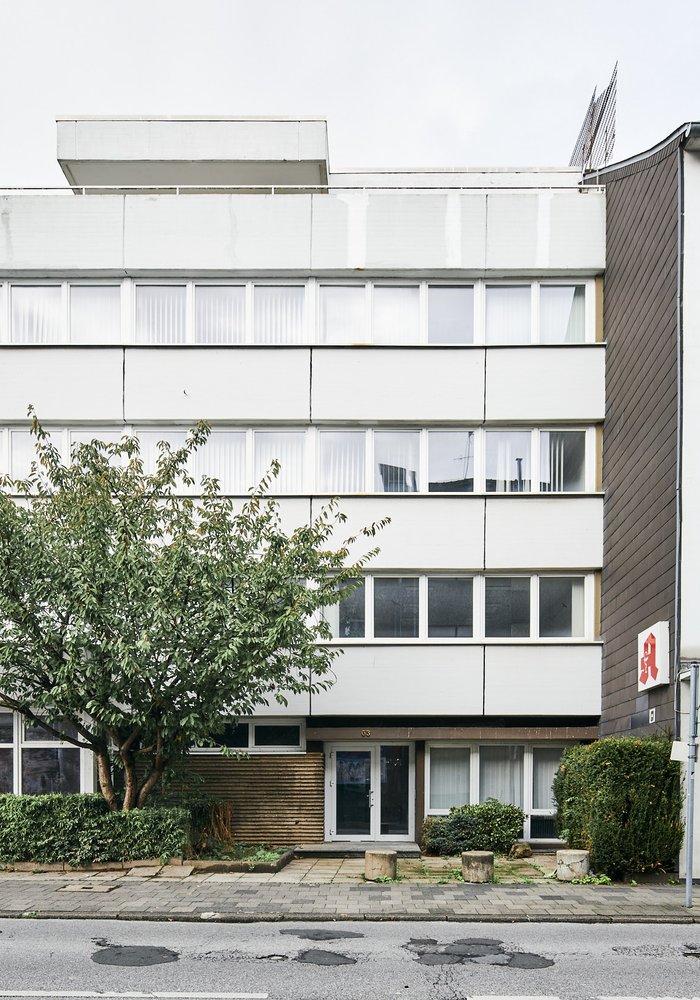 Blick auf die Fassade des hinteren Gebäudes. Es sind mehrere Fensterreihen und ein Teil der alten Apotheke zu sehen.