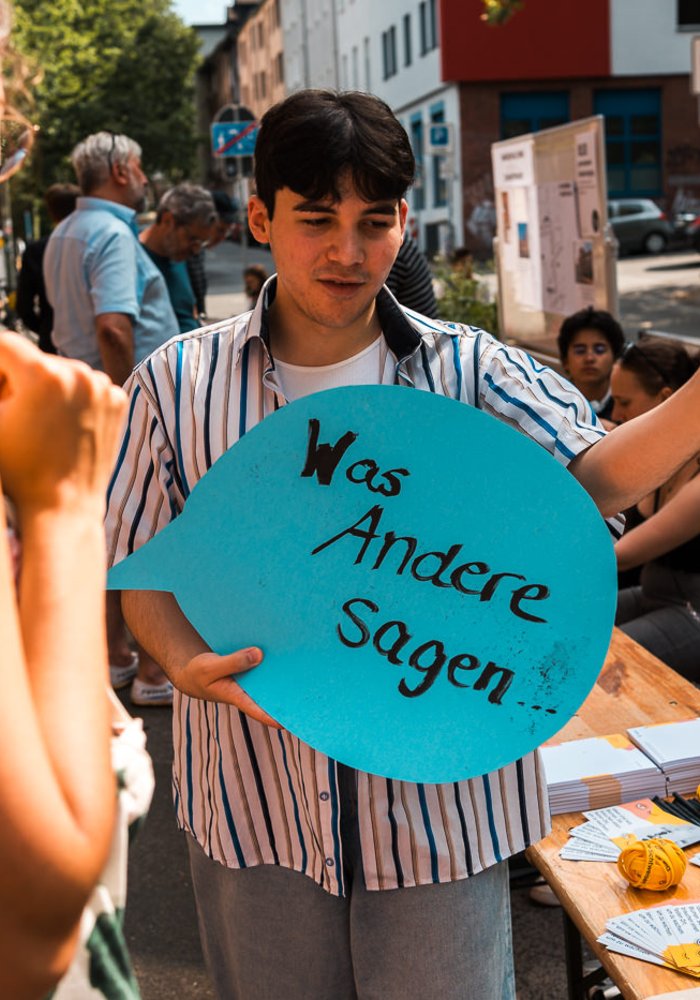 Ein Jugendlicher hält eine Sprechblase mit der Aufschrift: Was Andere sagen