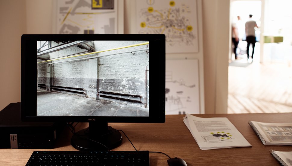 Ein Computer, der auf einem Schreibtisch steht und eine leere Wand zeigt.