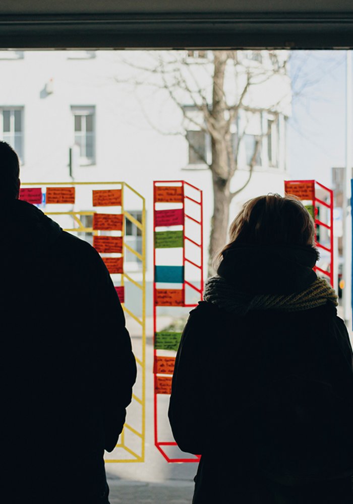 Drei Menschen stehen vor einer Fensterscheibe mit Post Its darauf.