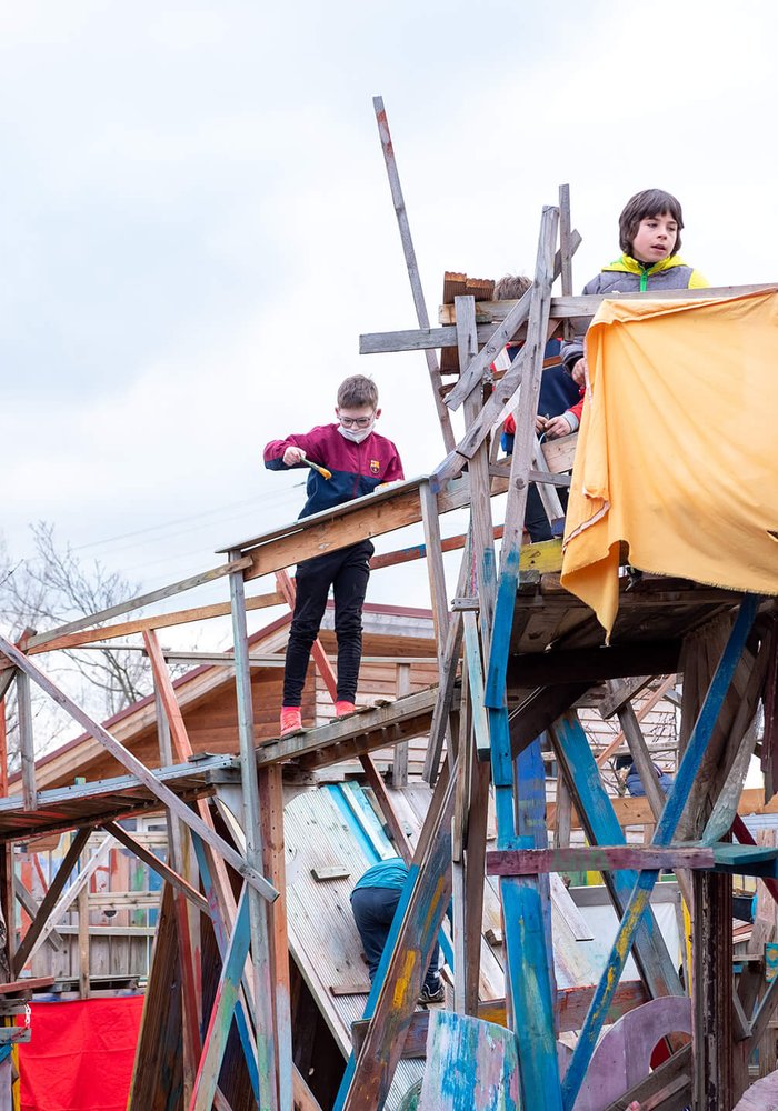 Kinder spielen auf einem bunten Holzgerüst, welches auf dem Bauspielplatz des Bürgerpark FreiFelds steht.