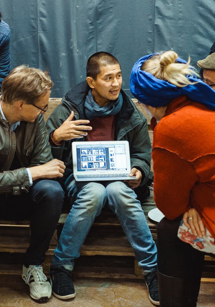 Ein Mann erklärt einer Gruppe von Menschen etwas auf einem Laptop.