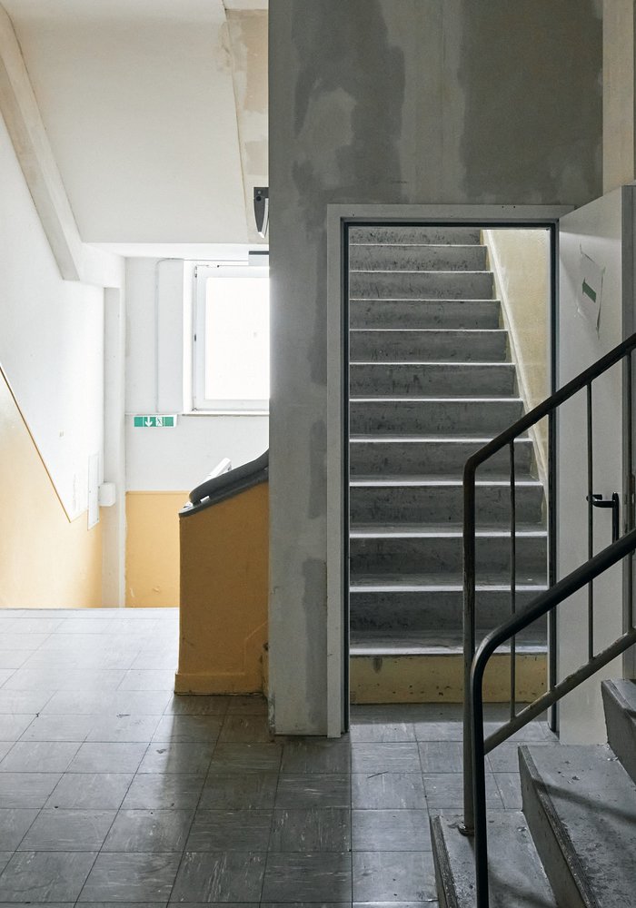 Ein altes Treppenhaus mit Blick auf mehrere Treppen und teils gelbe Wände.